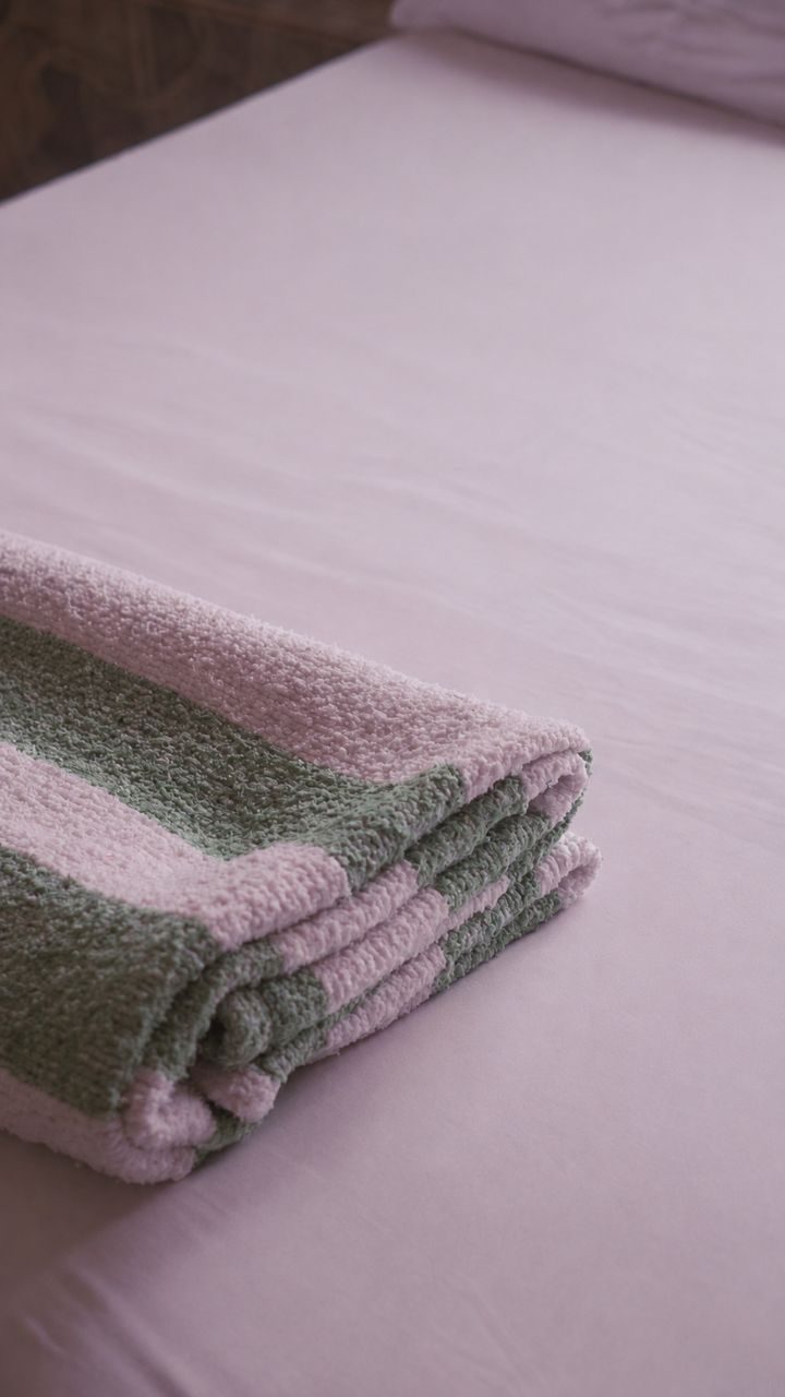 Toalla doblada sobre una cama recién tendida